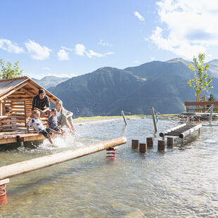 Kinder spielen am Montelinos Wasserspielplatz in Saalbach Hinterglemm im Sommer